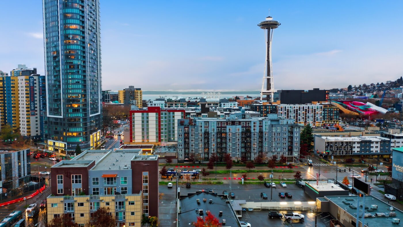 Aerial view of Seattle's skyline featuring the Space Needle, glassy high-rise and colorful mid-rise buildings with street traffic below.
