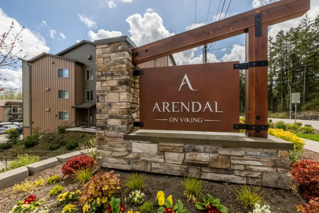Outdoor sign for Arendal on Viking apartment complex, mounted on a stone pedestal with a wooden frame